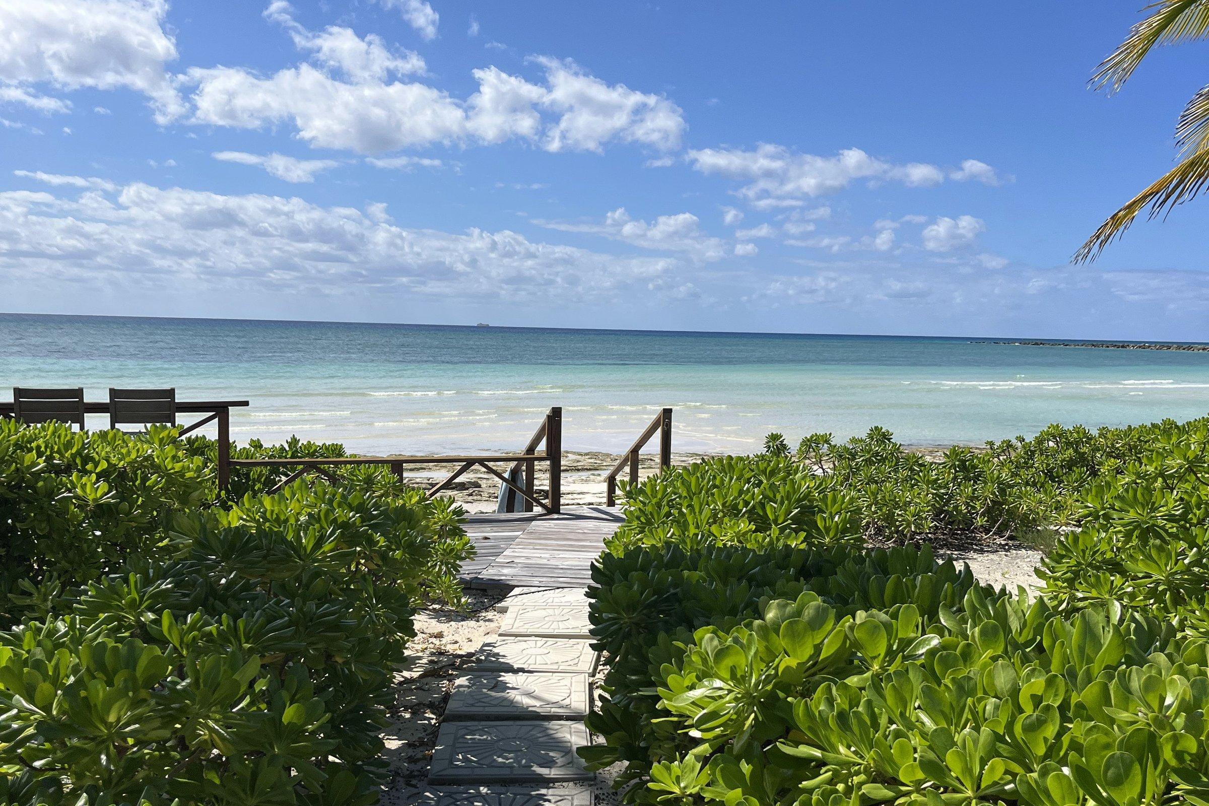 A stone path through sea grape down to a Bahamian beach