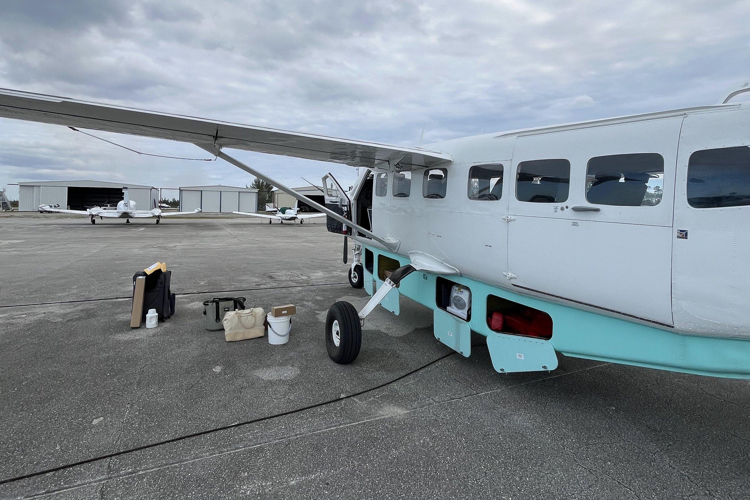 Bags staged on the ramp beside the Grand Caravan before loading